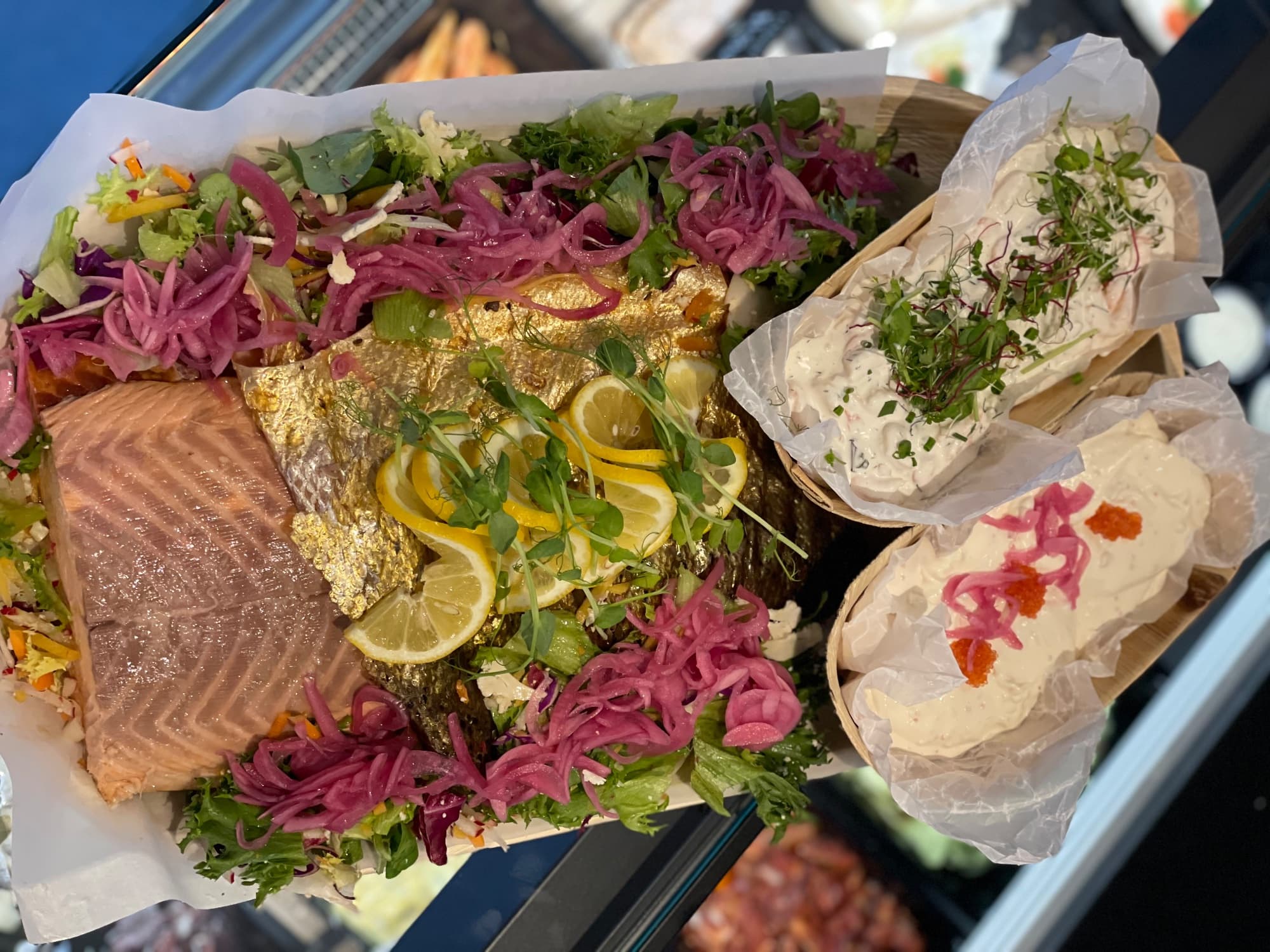Uppdukat laxfat med skivad lax, oskalade räkor, sallad, citron och picklad rödlök