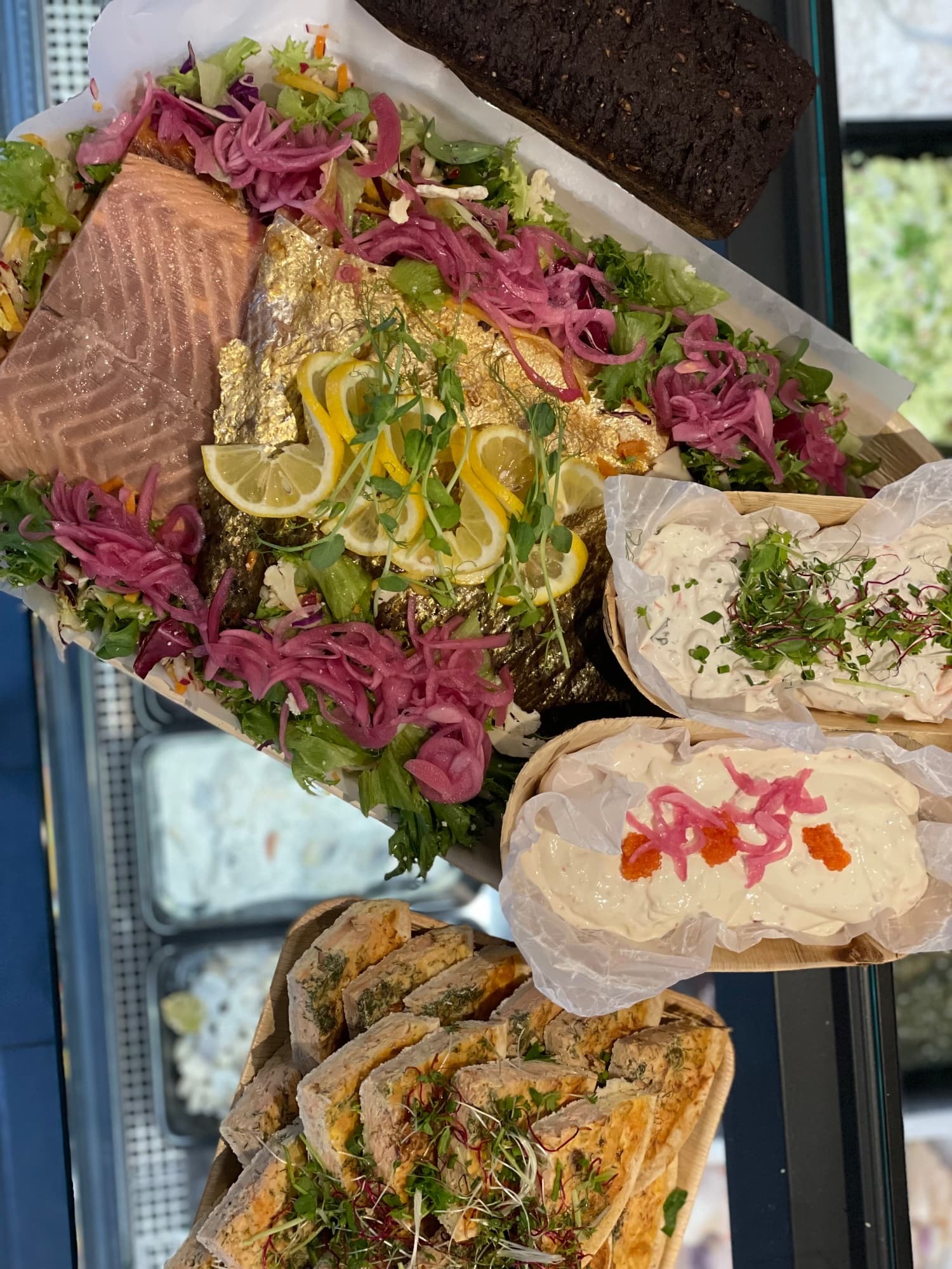 Uppdukat laxfat med skivad lax, oskalade räkor, sallad, citron och picklad rödlök
