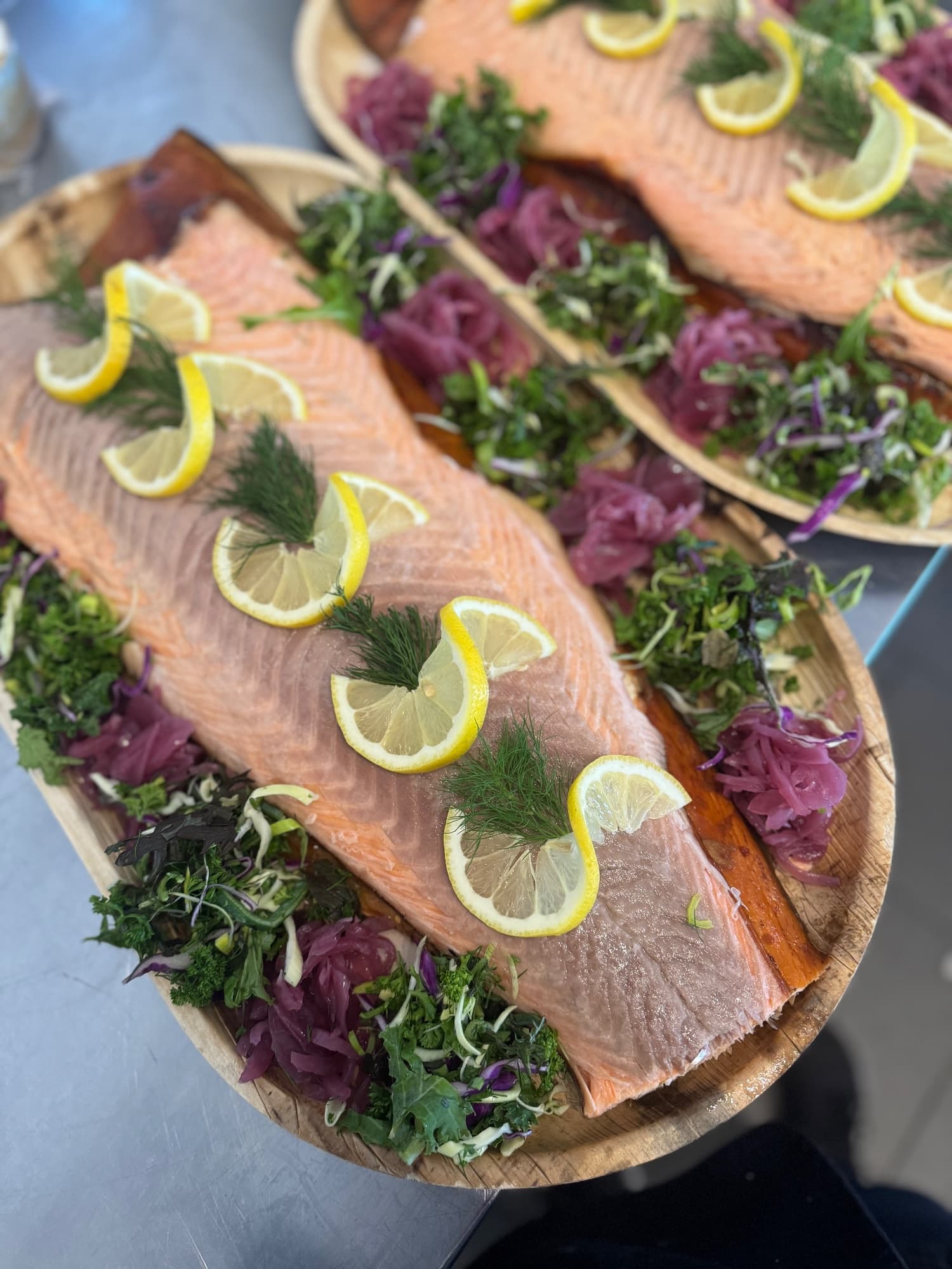 A laid-out salmon platter with sliced salmon, shell-on prawns, salad, lemon and pickled red onion