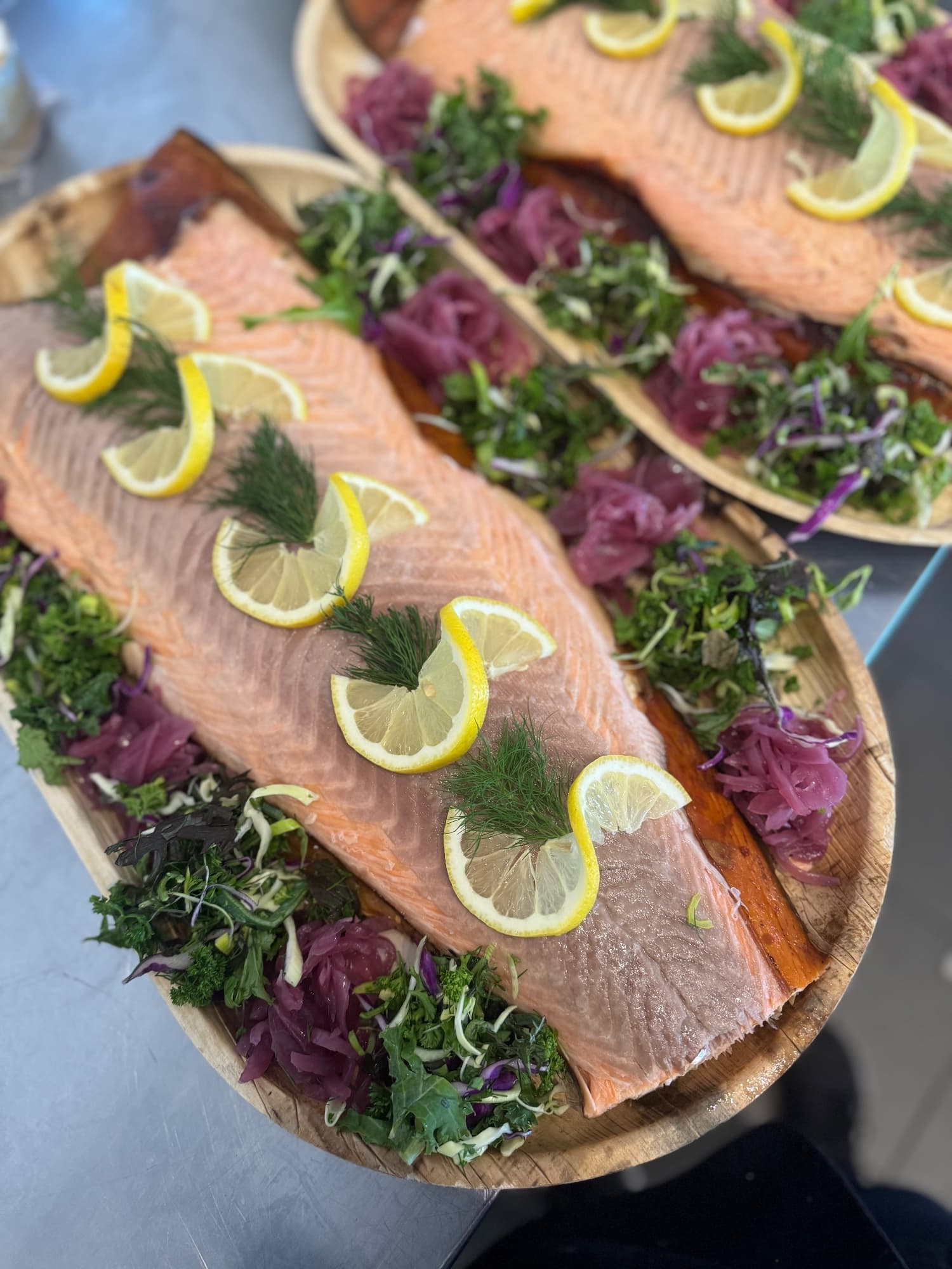 A laid-out salmon platter with sliced salmon, shell-on prawns, salad, lemon and pickled red onion